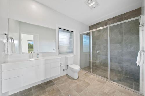a white bathroom with a toilet and a shower at The Chardonnay Villa at Molly Morgan Wines in Rothbury