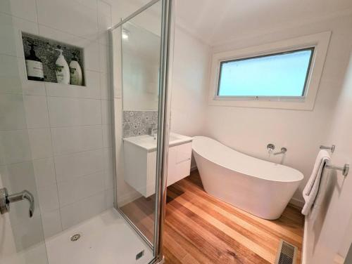 ein weißes Badezimmer mit Badewanne und Dusche in der Unterkunft Kookaburra Cottage- views, wineries, sanctuary, in Healesville