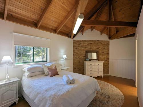 a bedroom with a large bed with two pillows on it at Sandys Pottery Cottage- pet friendly, wineries, in Healesville