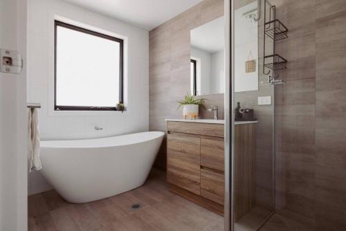 une salle de bain avec baignoire et douche en verre dans l'établissement The Drift Haus- Shearwater, à Port Sorell