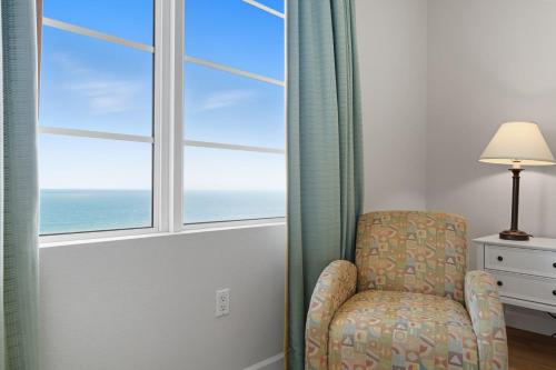 a chair in a room with a window at -New Listing- Completely Remodeled and Newly Furnished 3BR Direct Ocean Front Condo in Seabreeze