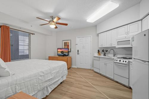 a white bedroom with a bed and a kitchen at -New Listing- Completely Remodeled and Newly Furnished 3BR Direct Ocean Front Condo in Seabreeze