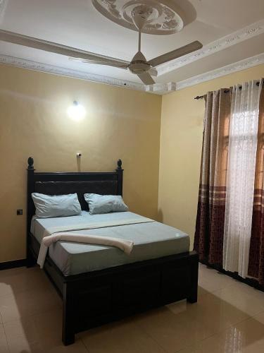 a bedroom with a bed with a ceiling fan at Mashingo Homestay in Dar es Salaam