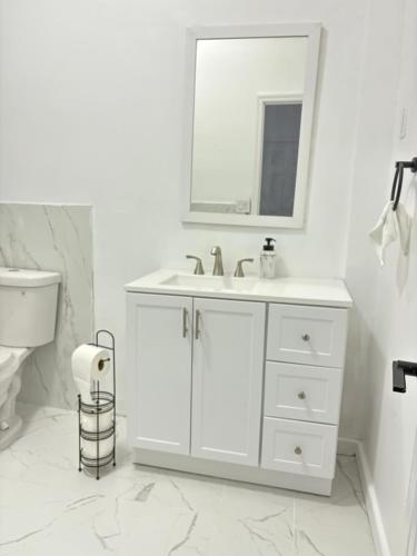 a white bathroom with a sink and a mirror at Luxury Apartments in Georgetown