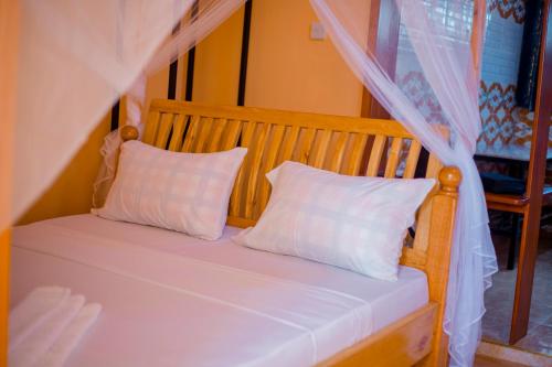 a bed with two white pillows and a canopy at Antelope homestay in Boma la Ngombe