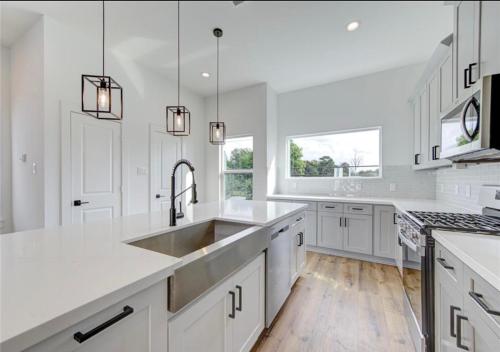 a kitchen with white cabinets and a stainless steel sink at Modern Home Suite, 2BR, Office, Near Galleria in Houston