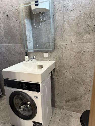 a bathroom with a washing machine and a sink at poilsio ramybes oaze in VNO