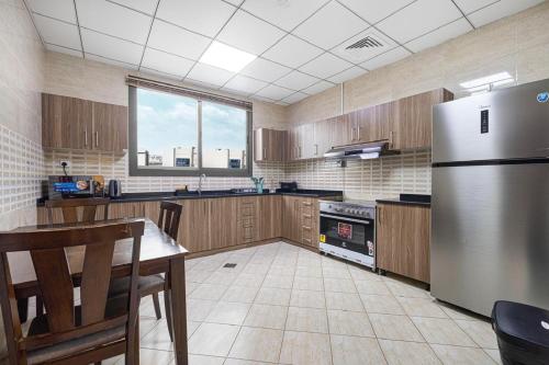 a kitchen with a stainless steel refrigerator and wooden cabinets at The Pearl Villa - Swimming Pool with Sea and Mountain view - Al Dana Island Fujaira in Fujairah