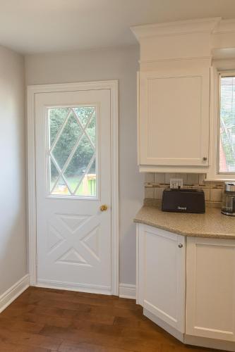 a kitchen with white cabinets and a white door at Spacious 5-Bedroom House in Thornhill in Vaughan