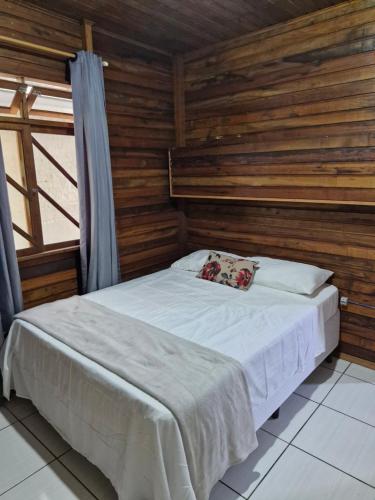 a bed in a room with a wooden wall at Apartamento 3,3km oktoberfest até 2 pessoas com opção de café da manhã in Blumenau