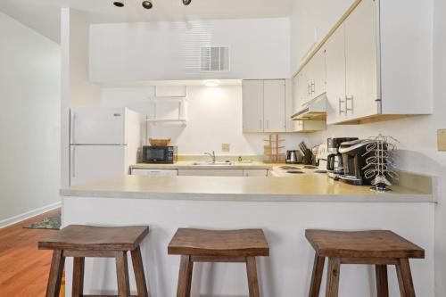 a kitchen with white cabinets and two wooden stools at Charming Soulard Retreat with Historic Character near Baseball Stadium apts in Soulard