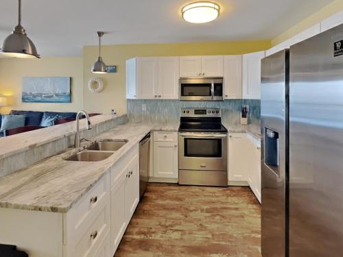 a kitchen with white cabinets and a stainless steel refrigerator at Put-in-Bay Waterfront Condo #208 in Put-in-Bay
