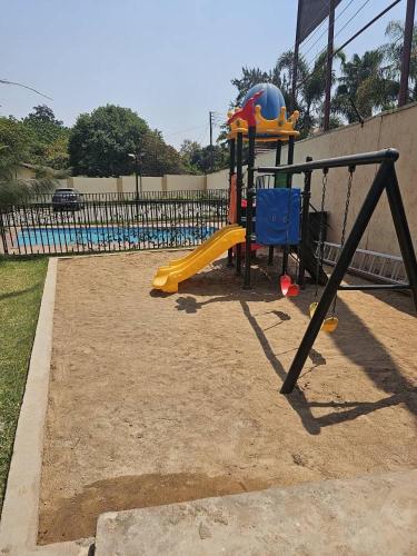 a playground with a slide and a swing at Ahava Home in Lusaka