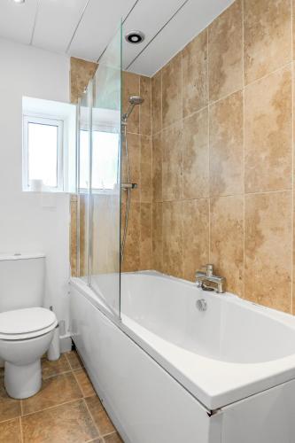 a bathroom with a tub and a toilet at Modern Bury Retreat - Free Parking, Easy Manchester Access in Tottington
