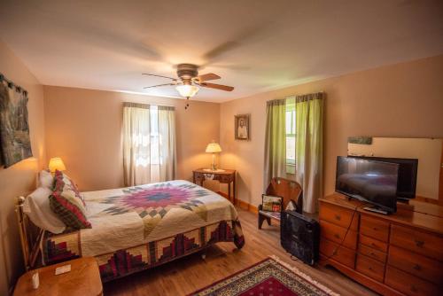 a bedroom with a bed and a flat screen tv at New River Farmhouse on the New River & Stocked Fishing Creek in Crumpler
