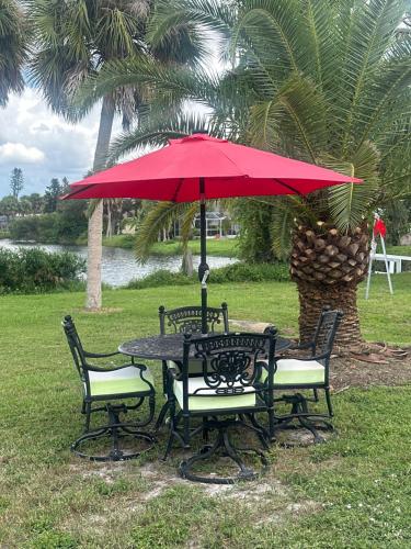 a table and chairs with a red umbrella at Magic Secluded Suite-Pool-Sauna plus Lake View Venice Florida in Venice