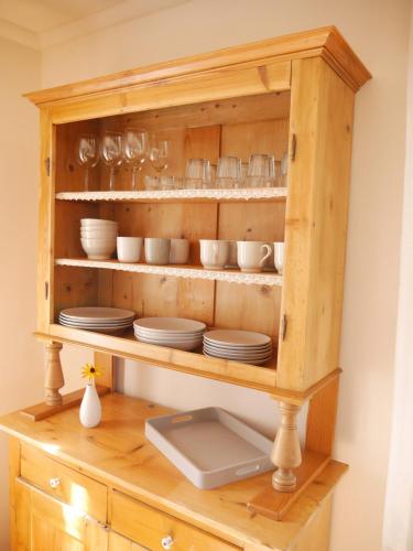 a wooden cabinet with plates and dishes in it at Gemütliche 95qm Wohnung mit eigenem Garten in Kottenheim