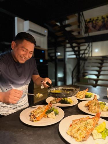 a man preparing food on a table with plates of food at Oceanfront 3 Bedroom - Conmigo Villas North in Maya Beach