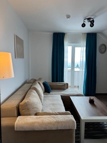 a living room with a large couch and blue curtains at Ramondia, Kopaonik in Kopaonik