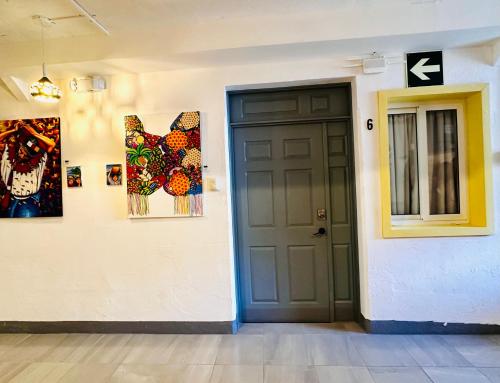 a hallway with a door and paintings on the wall at Hotel y Arte Antigua by Amazing Guatemala Travel in Antigua Guatemala