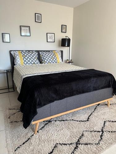 a bedroom with a bed with a black blanket on it at Maison d'hôtes chic à Beauzelle in Beauzelle