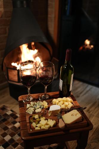 a table with two glasses and a bottle of wine and cheese at Chalé Petra - Recanto da Pedra in São Bento do Sapucaí