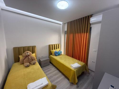 a room with two beds with a teddy bear sitting on them at Amaji Apartament Korcë in Korçë