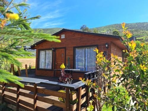 a log cabin with a wooden deck in front of it at La Serena Casa Cabaña de campo entre cactus y colibríes in La Serena