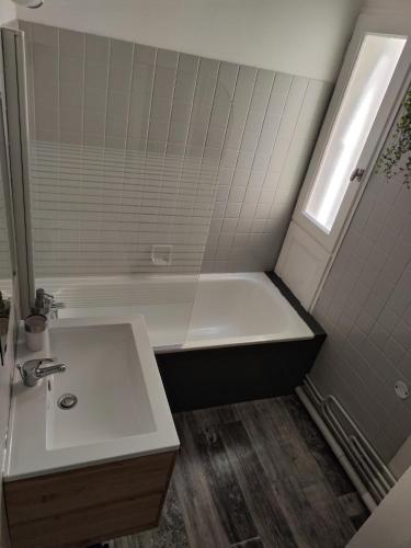 un bagno con vasca bianca e lavandino di Studio plein centre a Cauterets