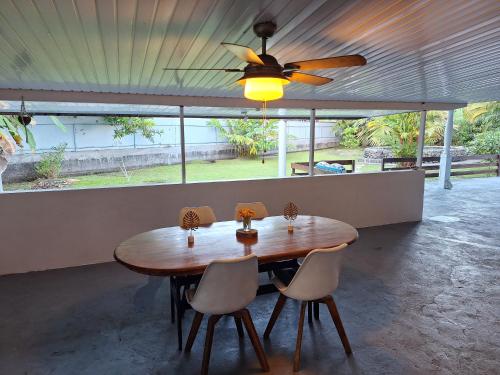 a dining room table with chairs and a ceiling fan at Fare blue Maeva in Papara