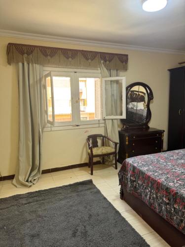 um quarto com uma cama, uma cadeira e uma janela em Comfyshorouk em Darb al Ḩājj