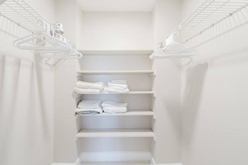 a white closet with white shelves and towels at Boca Beach Retreat • Pool • Sand in Boca Raton