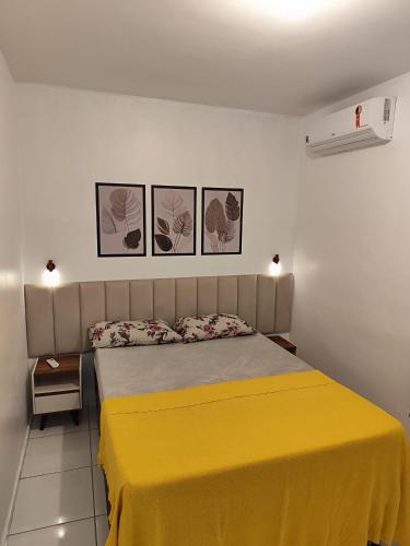 a bedroom with a yellow bed with three pictures on the wall at Cantinho da harmonia-Morada Nova in Petrolina