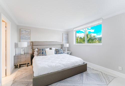 a white bedroom with a large bed and a window at Boca Beach Retreat • Pool • Sand in Boca Raton