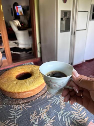 a person holding a cup of coffee and a bagel at Fazenda Montanhes in Visconde De Maua