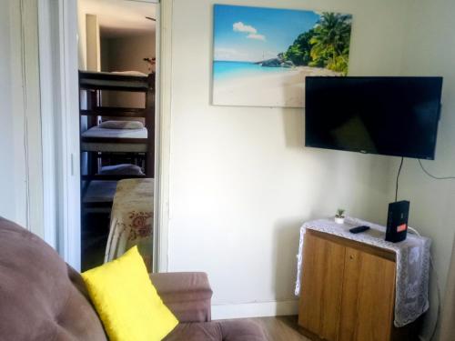a living room with a couch and a flat screen tv at Frente ao Mar Residence in São Vicente