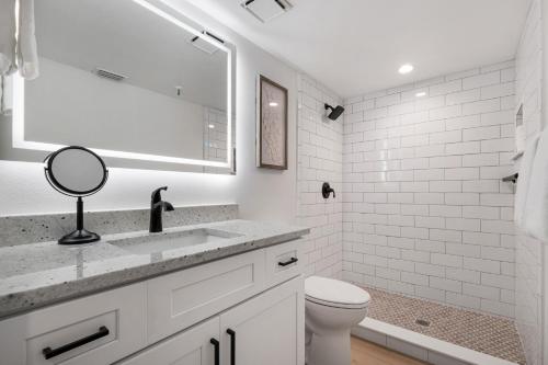 a white bathroom with a sink and a toilet at Updated direct oceanfront, ground floor condo with a heated pool and beach access in Bottle Island