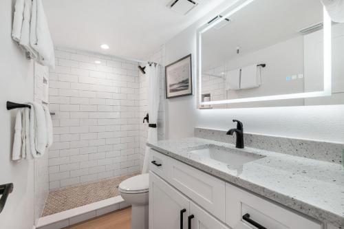 a white bathroom with a sink and a toilet at Updated direct oceanfront, ground floor condo with a heated pool and beach access in Bottle Island