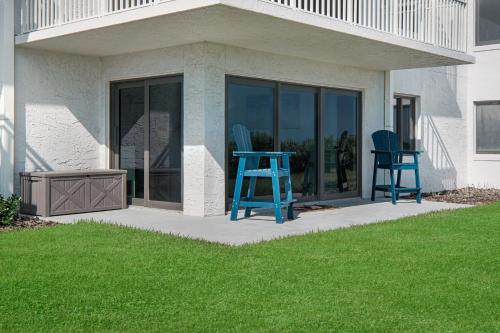 two blue chairs and a table on a patio at Updated direct oceanfront, ground floor condo with a heated pool and beach access in Bottle Island