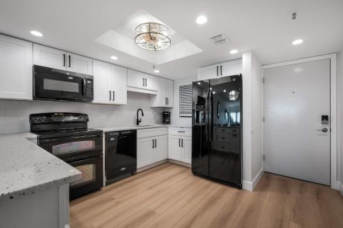 a kitchen with white cabinets and a black refrigerator at Updated direct oceanfront, ground floor condo with a heated pool and beach access in Bottle Island