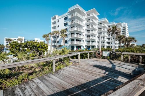 a large white building on the beach with a wooden boardwalk at Updated direct oceanfront, ground floor condo with a heated pool and beach access in Bottle Island