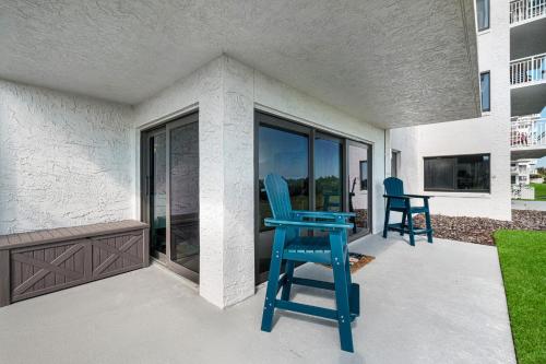 a blue chair sitting on a porch with a balcony at Updated direct oceanfront, ground floor condo with a heated pool and beach access in Bottle Island