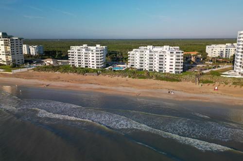 an aerial view of a beach with buildings and the ocean at Updated direct oceanfront, ground floor condo with a heated pool and beach access in Bottle Island