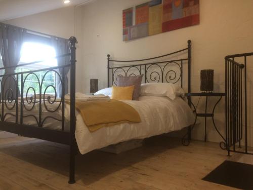 a bedroom with a black metal bed with pillows at Coach House Studio, quiet, rural, pet friendly, Probus in Probus