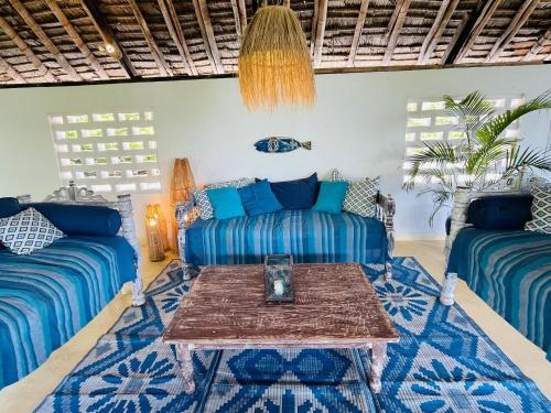 a living room with blue couches and a table at Self catering Beach House on award winning marine conservancy in Kijangwani