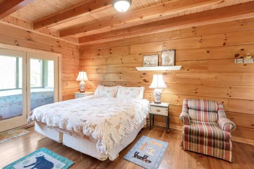 a bedroom with wooden walls and a bed and a chair at Lazy Dog Log Cabin, Hot Tub, Fishing Lake, New River Access, Foosball in Wagoner