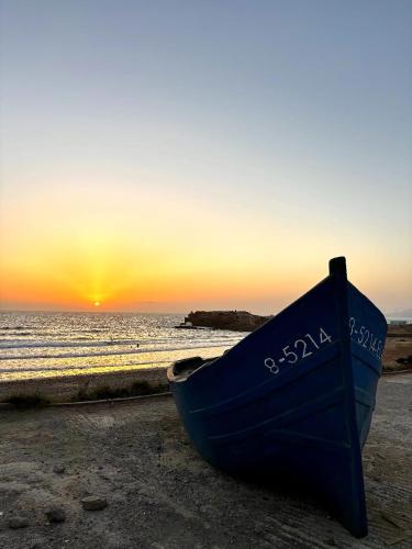 a blue boat sitting on the beach at sunset at Dar Surfana Morocco in Aourir