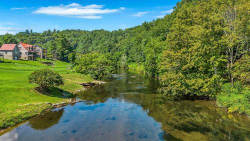 a river with a house in the background next to a forest at Cozy Cabin Right on the New River in Todd - Easy River Access - Fire Pit in Brownwood