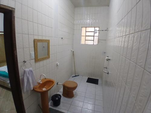 a white tiled bathroom with a toilet and a sink at Pousada Imperatriz in Aparecida