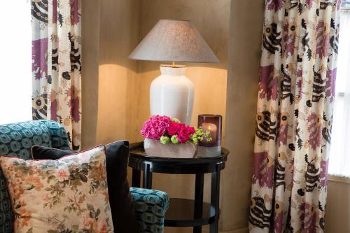 a lamp on a table next to a chair with flowers at Les Tournelles in Paris